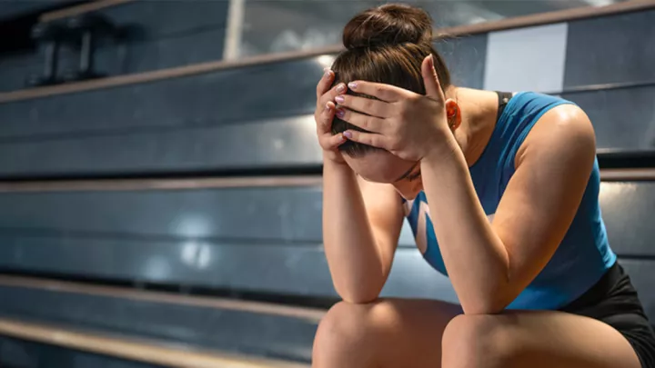 Woman sitting on bleachers with head in hands