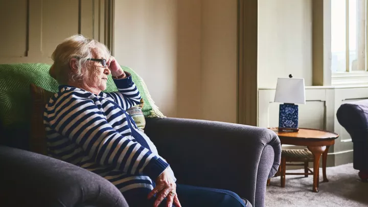 An older woman holding her head in her hand